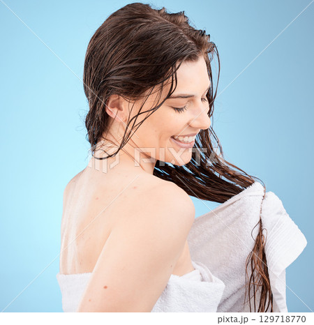 Haircare, washing and cleaning hair and a woman drying her hair with a towel on a blue studio background. Salon, hair style and hair care with a clean female after hair wash with wet hair Haircare, washing and cleaning hair and a woman drying her hair with a towel on a blue studio background. Salon, hair style and hair care with a clean female after hair wash with wet hair 129718770