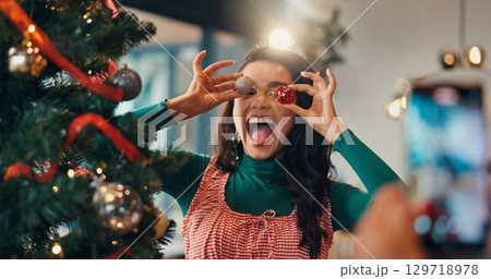 Christmas tree, funny and picture with woman and ornament for festive season, memory and decoration. Merry xmas, holiday and photography with silly person in living room of home for happy and bauble Christmas tree, funny and picture with woman and ornament for festive season, memory and decoration. Merry xmas, holiday and photography with silly person in living room of home for happy and bauble 129718978