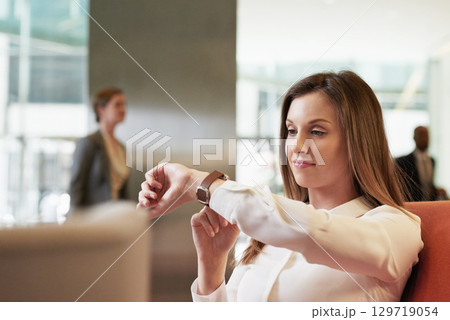 Time, watch and business woman in a corporate lobby, waiting and working at a company. Management, executive and impatient manager with a smart watch check at a professional lounge for networking 129719054