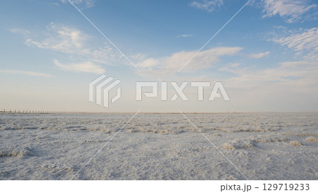 Landscape of a salt lake with a flat white surface under the light of a blue sky. Lake Baskunchak in the Astrakhan region of Russia. 129719233