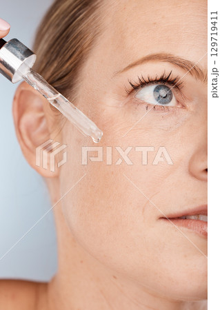 Face, skincare and serum with a model woman in studio on a gray background to promote a cosmetic product. Facial, beauty and antiaging with a female applying oil to her skin for natural cosmetology Face, skincare and serum with a model woman in studio on a gray background to promote a cosmetic product. Facial, beauty and antiaging with a female applying oil to her skin for natural cosmetology 129719411