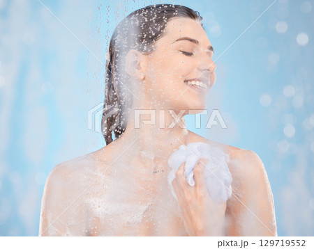 Water, soap and skincare with woman in shower for beauty, self care and hygiene routine. Relax, luxury and spa with girl model and sponge for cosmetics, salon or cleaning in blue background in studio Water, soap and skincare with woman in shower for beauty, self care and hygiene routine. Relax, luxury and spa with girl model and sponge for cosmetics, salon or cleaning in blue background in studio 129719552