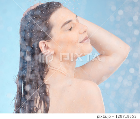 Water, shower and woman cleaning body on blue background of healthy skincare, beauty or wellness. Young studio model, water drops and personal hygiene, bathroom and cosmetics, self care or fresh face Water, shower and woman cleaning body on blue background of healthy skincare, beauty or wellness. Young studio model, water drops and personal hygiene, bathroom and cosmetics, self care or fresh face 129719555