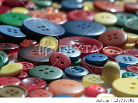 a close-up of a pile of colorful sewing buttons of various sizes and shades and patterns. Craft background, 129719592