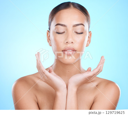 Skincare, hands and face of woman in studio for natural healing, youth glow and skin wellness on blue mockup for marketing. A young beauty model, facial cosmetics and makeup promotion for dermatology 129719625