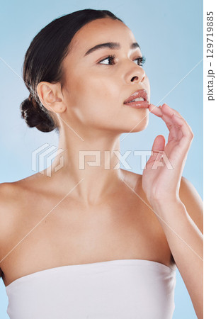 Wellness, cosmetic and beauty skincare with woman lips and face posing isolated in studio against a blue background. Attractive female model looking confident and healthy with her daily skin routine 129719885
