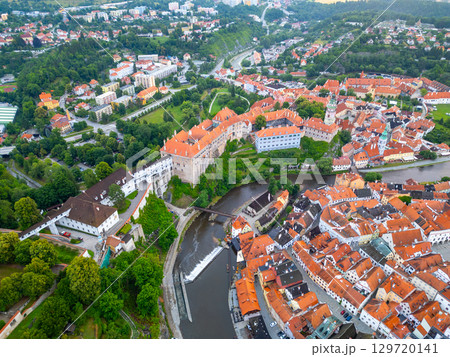 The captivating town of Cesky Krumlov is bathed in morning light, showcasing its iconic castle, colorful rooftops, and the winding Vltava River. 129720141