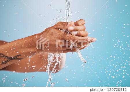 Water, washing and cleaning hands on blue background for hygiene, healthcare and cleansing in studio. Wellness, hydration and person washing hands for germ protection, bacteria and safety from virus 129720512