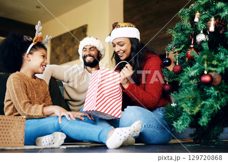 Christmas, love and family opening gifts in home, having fun and bonding on holiday. Xmas spirit, care and happy father, mother and girl exchange presents in living room and enjoying quality time. 129720868