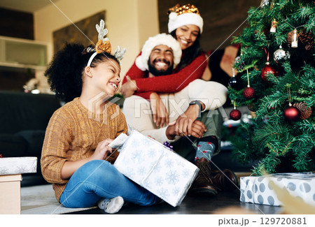 Mother, father and girl with a Christmas gift hugging to celebrate love, happy family and winter holidays at home. Love, mom and excited dad in santa hat giving a young child or kid a surprise box 129720881