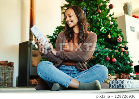 Christmas, celebrate holiday and woman with gift, opening and happy on living room floor by Christmas tree. Home, festive with present box and happiness, excited about traditional xmas celebration. 129720936