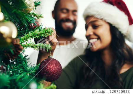Christmas, decorating tree and happy black couple celebrate holiday season with love, happiness and festive bonding. Black woman, man smile together and enjoy decorate Christmas tree in living room 129720938