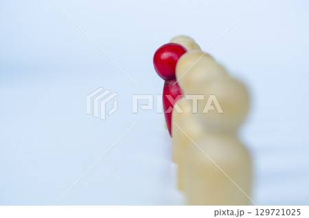 A single red figure voicing out from other wooden figures, representing leadership or unfair treatment or discrimination concept A single red figure voicing out from other wooden figures, representing leadership or unfair treatment or discrimination concept 129721025