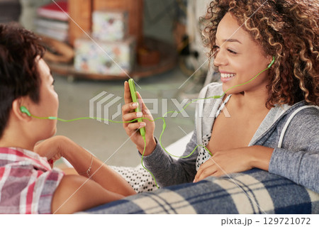 Women, friends and phone while listening to music on sofa with smile, happiness and home wifi for streaming podcast or radio. Happy female with lesbian partner and media player for entertainment Women, friends and phone while listening to music on sofa with smile, happiness and home wifi for streaming podcast or radio. Happy female with lesbian partner and media player for entertainment 129721072