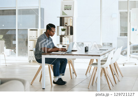 Creative, designer and laptop in web design or online marketing, advertising or development at the office. Black man employee working on computer in design for corporate company at the workplace 129721127