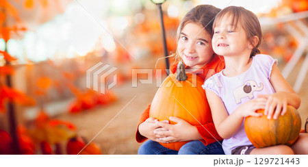 Two Girls Holding Their Pumpkins At A Pumpkin Patch on a Fall Day. 129721443
