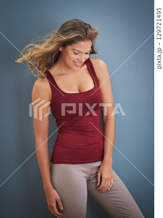 Happy woman, fitness and smile on studio background while thinking about memory, motivation and body. Shy model in exercise clothes for inspiration and positive mindset while standing by blue wall Happy woman, fitness and smile on studio background while thinking about memory, motivation and body. Shy model in exercise clothes for inspiration and positive mindset while standing by blue wall 129721495