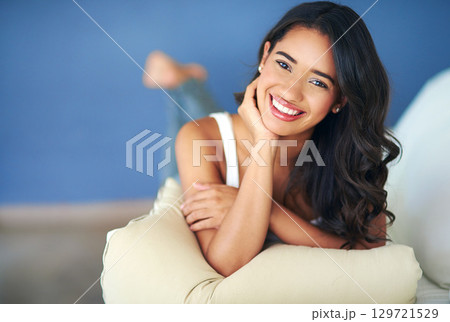 Portrait, woman and lying on sofa, relax and happy in living room being calm. Confident female, girl and happiness to rest, with smile and peaceful for weekend, break and with joy on couch in lounge. 129721529