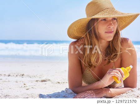 Woman, beach and sunscreen while on a tropical vacation in Bali for rest and relaxation. Skincare, protection and suncream with a female tourist on a seaside holiday while using cream on the sand 129721570