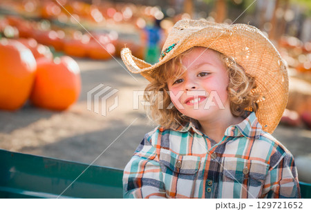 Cute Young Boy Wearing Cowboy Hat at Pumpkin Patch Farm. Cute Young Boy Wearing Cowboy Hat at Pumpkin Patch Farm. 129721652