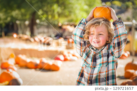 Cute Young Boy Having Fun at the Pumpkin Patch on a Sunny Fall Day. 129721657