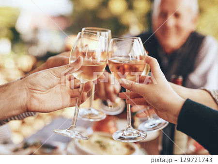 Hands, glass and cheers with a group of people drinking alcohol together outdoor in celebration of the festive season. Party, wine and drink with a man and woman family doing cheers to tradition 129721743