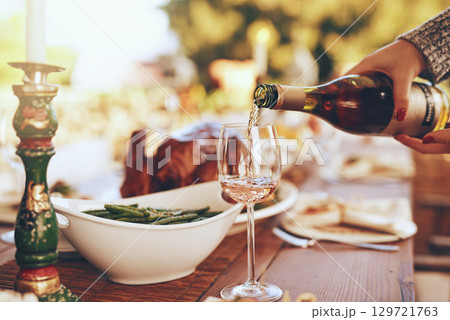 Champagne, dinner and hands with a woman pouring a drinking during a Christmas party outdoor. Tradition, celebration and alcohol with a feast on a wooden table for a social gathering outside 129721763