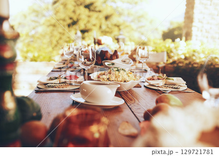 Food, celebration and dinner party in a garden for fine dining, nutrition and table setting. Lunch, celebration and tradition on a patio with a prepared dinner on a table in the backyard of a house 129721781