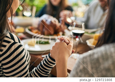 Food, praying and family holding hands for prayer with parents and children gathering at a dinner table at home. God, worship and grateful people with gratitude enjoy a thanksgiving meal with turkey Food, praying and family holding hands for prayer with parents and children gathering at a dinner table at home. God, worship and grateful people with gratitude enjoy a thanksgiving meal with turkey 129721808