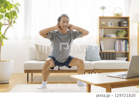 自宅リビングでトレーニングをするシニア男性　宅トレイメージ 129721820
