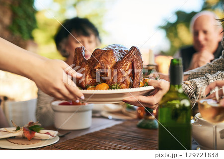 Thanksgiving, turkey and hands with a family eating a meal outdoor together in celebration of tradition. Christmas, chicken and party with a man and woman group enjoying dinner while bonding Thanksgiving, turkey and hands with a family eating a meal outdoor together in celebration of tradition. Christmas, chicken and party with a man and woman group enjoying dinner while bonding 129721838