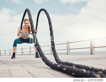 Fitness, woman and battle rope at the beach for intense arm workout, training or exercise in Cape Town. Active female exercising with ropes for cardio, muscle endurance or power in the outdoors 129722065