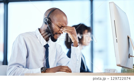 Stress, burnout and headache by call center worker, employee and customer service consultant in office. Pain, mental health and depressed telemarking agent overworked and frustrated at the workplace 129722074
