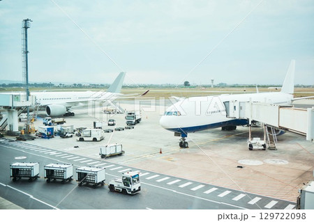 Airplane at airport, stationary transport on tarmac and runway for international passenger travel on sky horizon. Plane on ground, outdoor flight terminal and cargo carrier on aeroplane runway 129722098