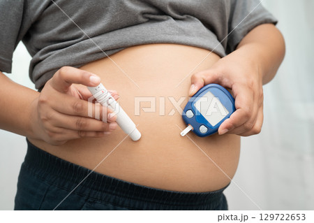 Asian woman injecting herself diabetes injecting insulin in stomach at home. 129722653
