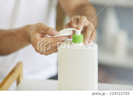 Close-up of male hands holds cotton pad and dispensing liquid cosmetic product Close-up of male hands holds cotton pad and dispensing liquid cosmetic product 129722785