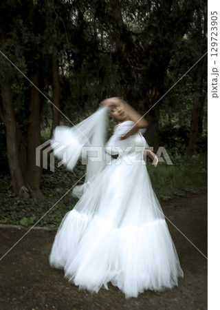 a bride in a white dress and a long veil stands among the trees a bride in a white dress and a long veil stands among the trees 129723905