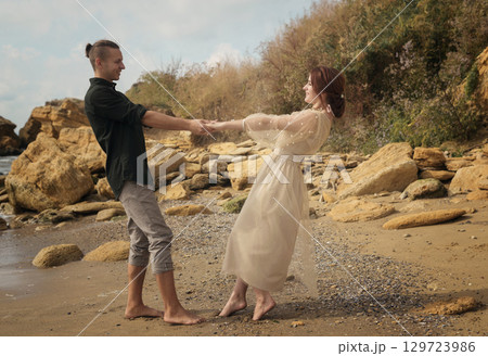 Romantic and smiling couple dancing on the seashore. Romantic and smiling couple dancing on the seashore. 129723986
