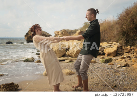 Romantic and smiling couple dancing on the seashore. 129723987