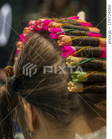 In a beauty salon, a girl is getting her hair curled In a beauty salon, a girl is getting her hair curled 129724060