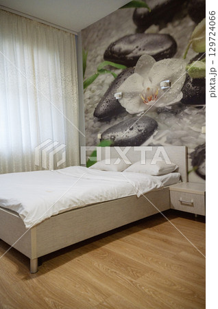 Double bed with pillows and light from the window. 129724066