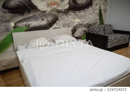 Double bed with two pillows, next to it is an armchair Double bed with two pillows, next to it is an armchair 129724072