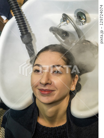 In a beauty salon, a girl client is getting her hair straightened 129724074