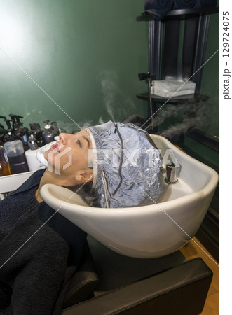 In a beauty salon, a girl is undergoing a hair procedure 129724075
