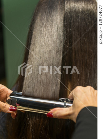In a beauty salon, a girl's hair is straightened 129724077