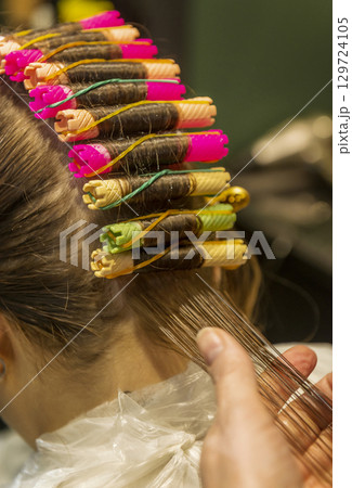 In a beauty salon, a girl is getting her hair curled In a beauty salon, a girl is getting her hair curled 129724105