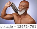 Shower, hygiene and towel with a senior black man in studio on a purple background for cleaning or skincare. Health, beauty and wellness with a mature male washing in the bathroom for luxury care 129724791