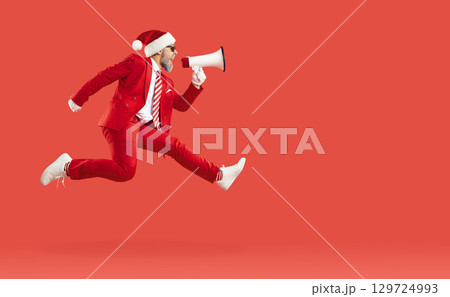 Old man in Santa style, Xmas cap jumping hurrying up screaming loudspeaker in air on red background. Old man in Santa style, Xmas cap jumping hurrying up screaming loudspeaker in air on red background. 129724993