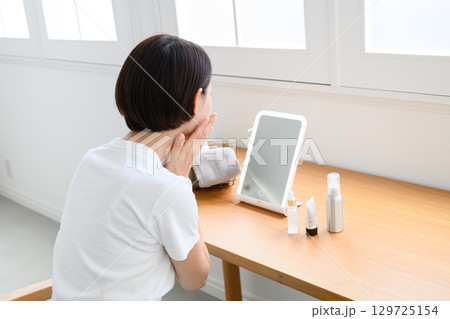 自宅でスキンケアをする女性 自宅でスキンケアをする女性 129725154