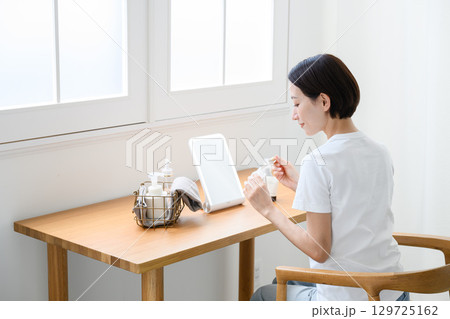 自宅でスキンケアをする女性 自宅でスキンケアをする女性 129725162